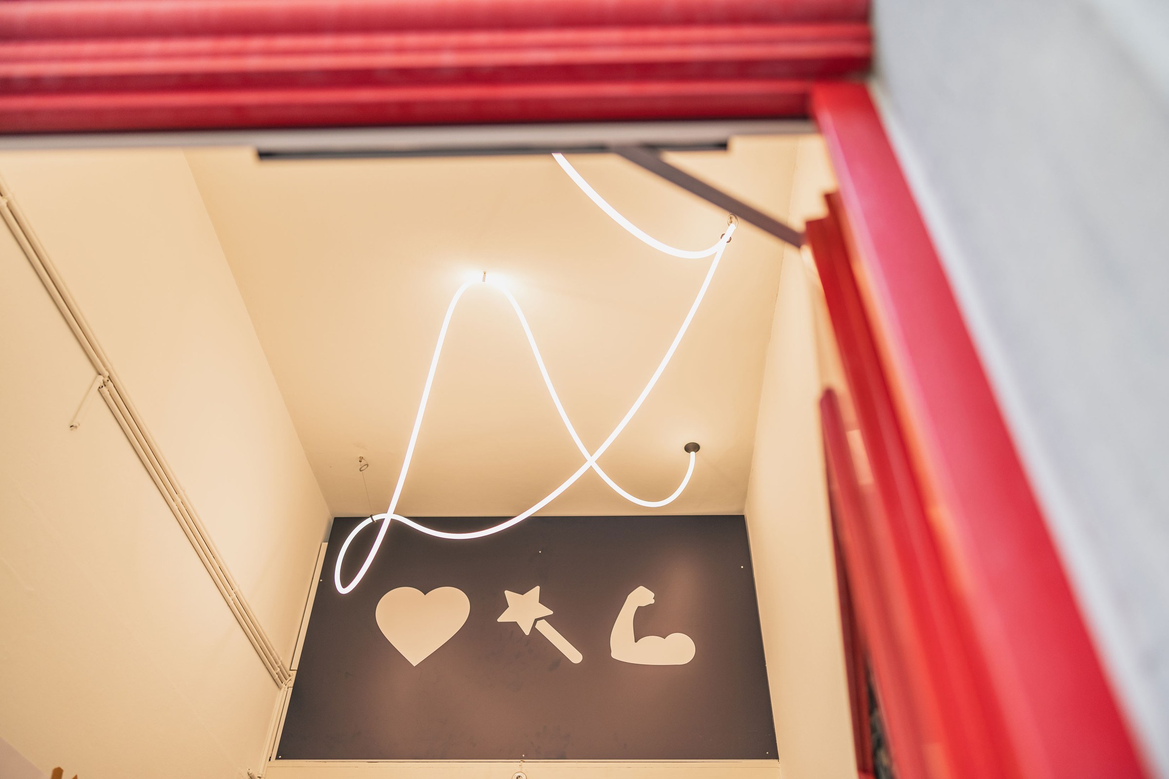 Abstrakte Neon-Lichtinstallation über grafischen Wandicons in einem modernen Innenraum.