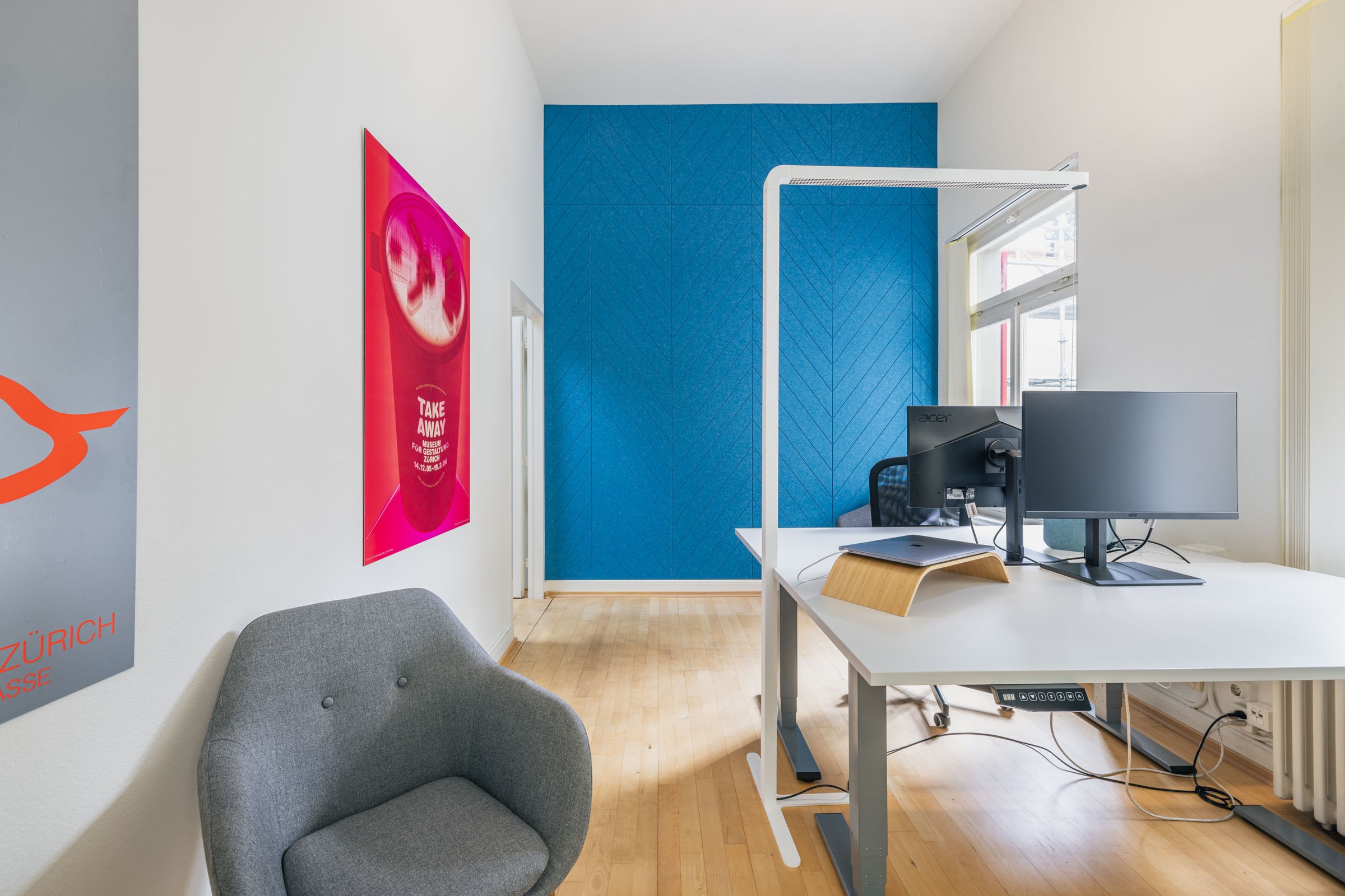 Büro mit grauem Sessel im Vordergrund.