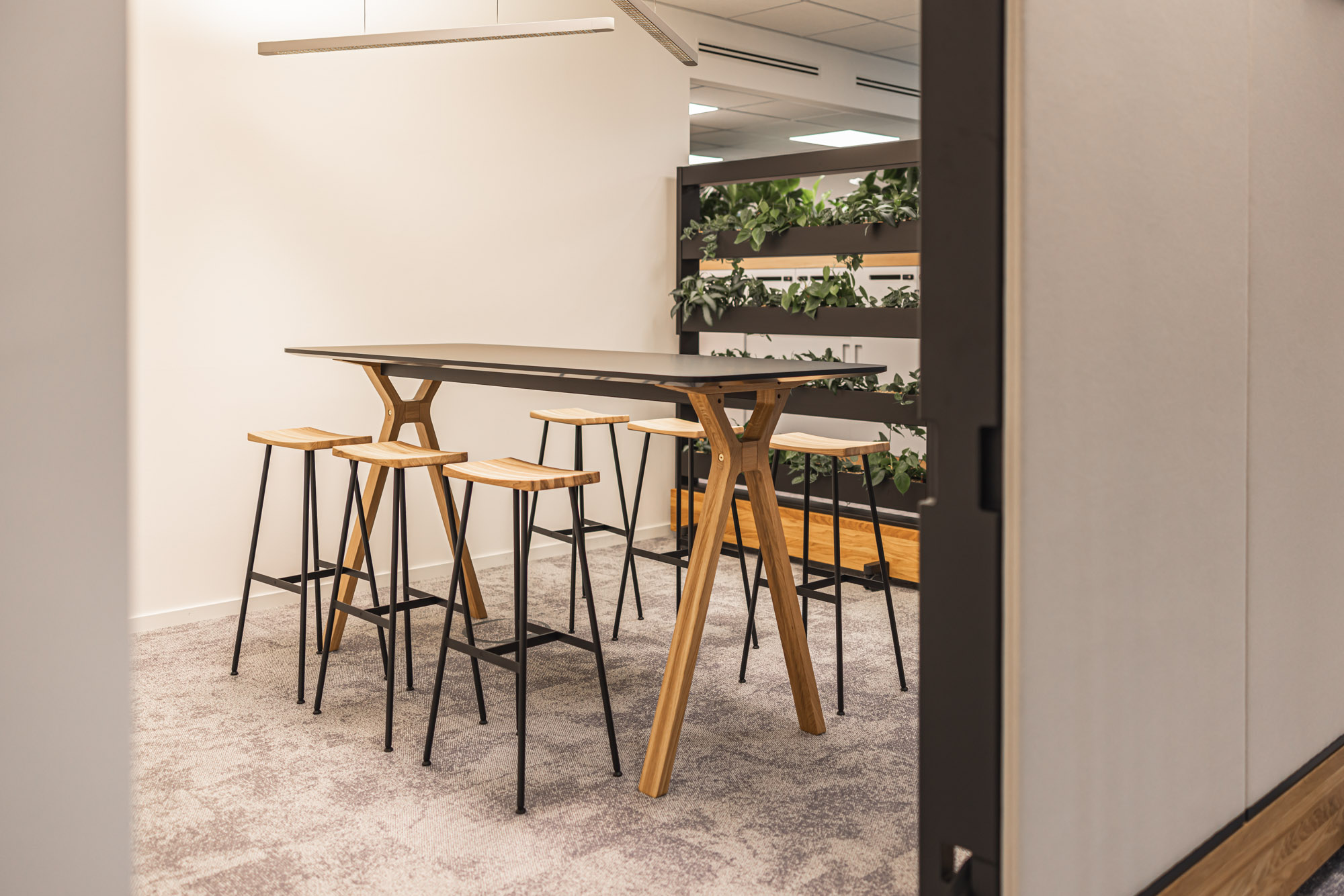 Meeting-Spot mit Holz-Hochtisch und Barhockern. Minimalistisch und kommunikativ.