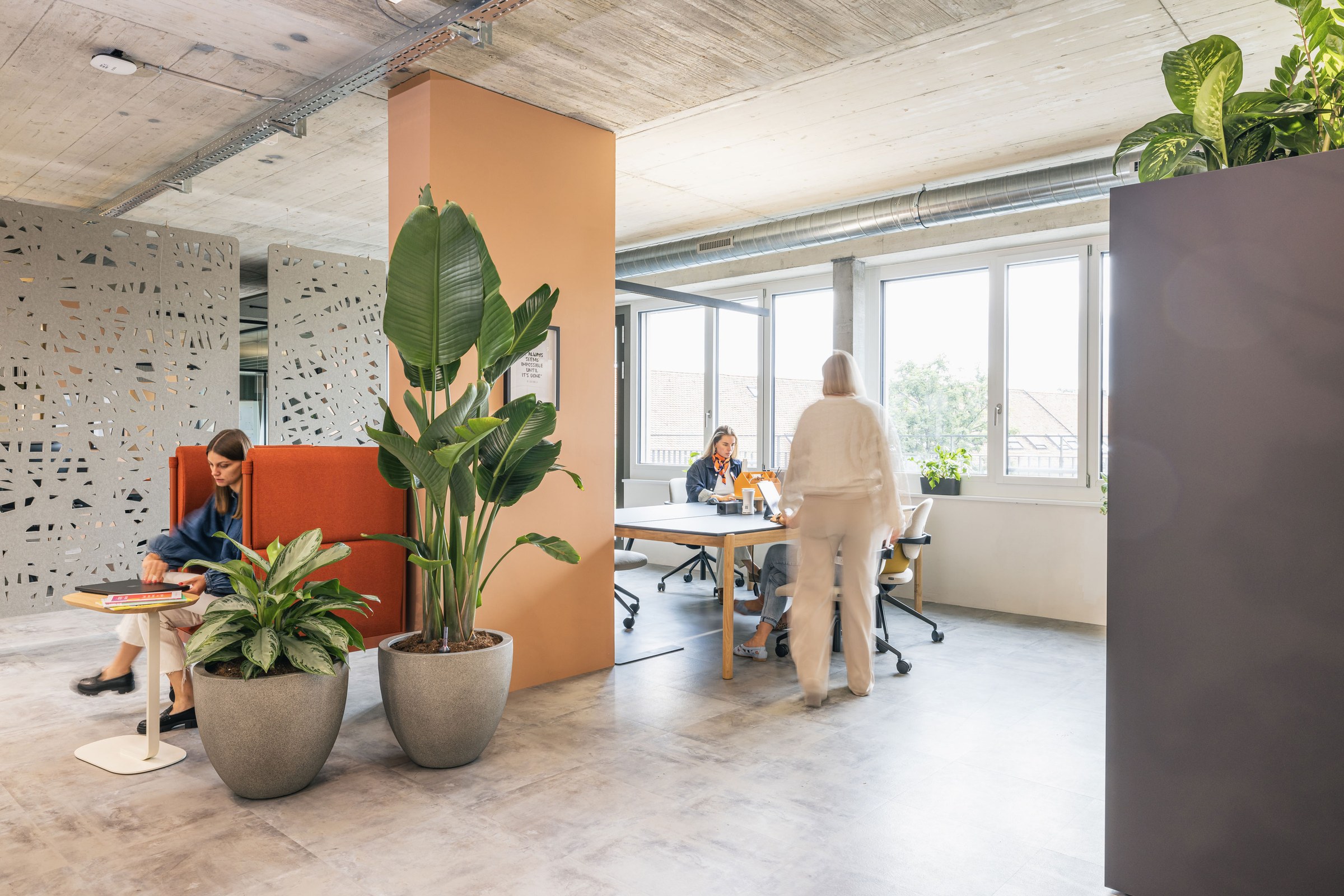 Offener Teamarbeitsbereich mit Lounge-Nischen, Pflanzen und modernem Industrieloft-Charakter.