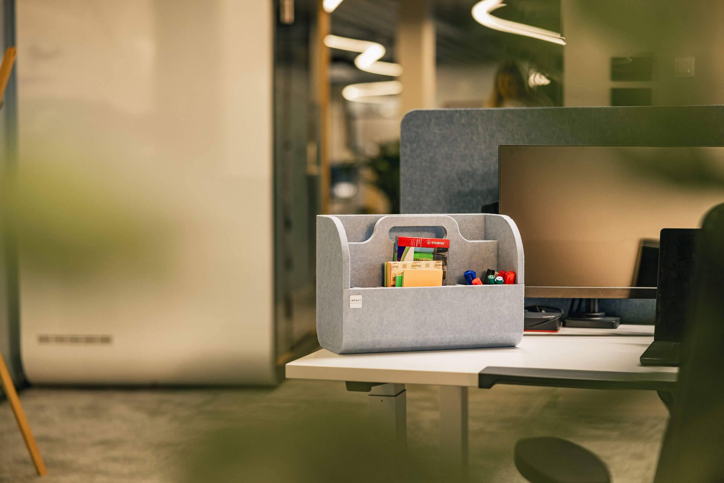 Grauer Büro-Organizer mit Stiften und Notizen auf einem modernen Arbeitsplatz.