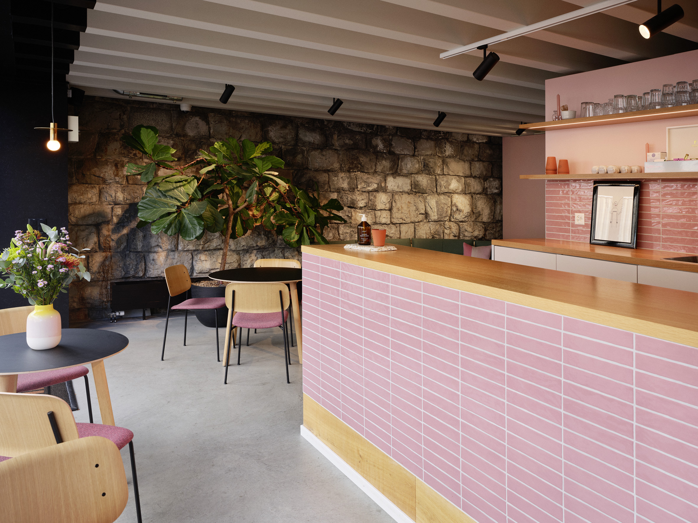 Nahaufnahme eine Theke mit pinken Kacheln. Daneben Coffee-Table mit Stühlen.