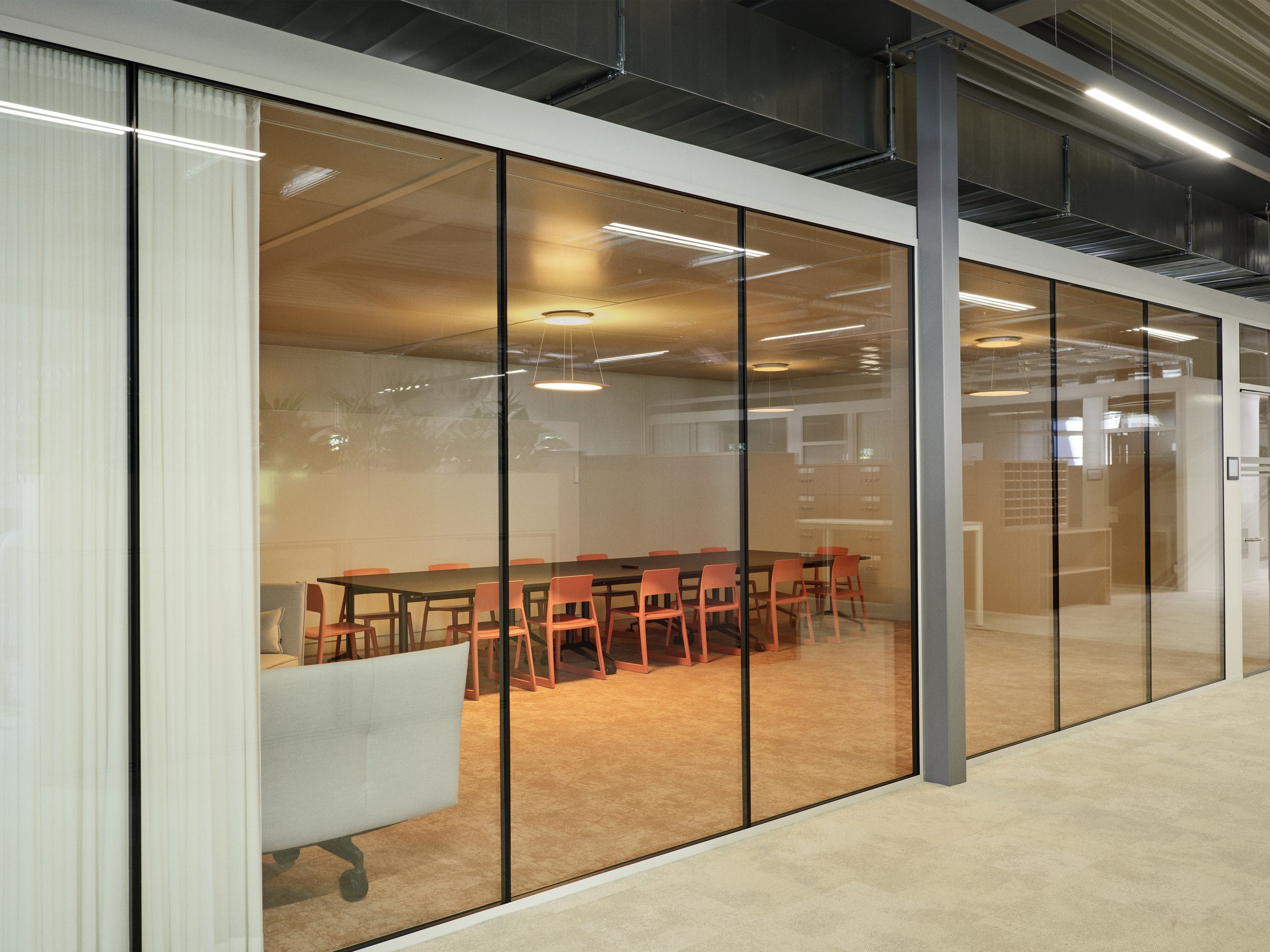 Glasscheibe zum Workshopraum mit bunten Stühlen.
