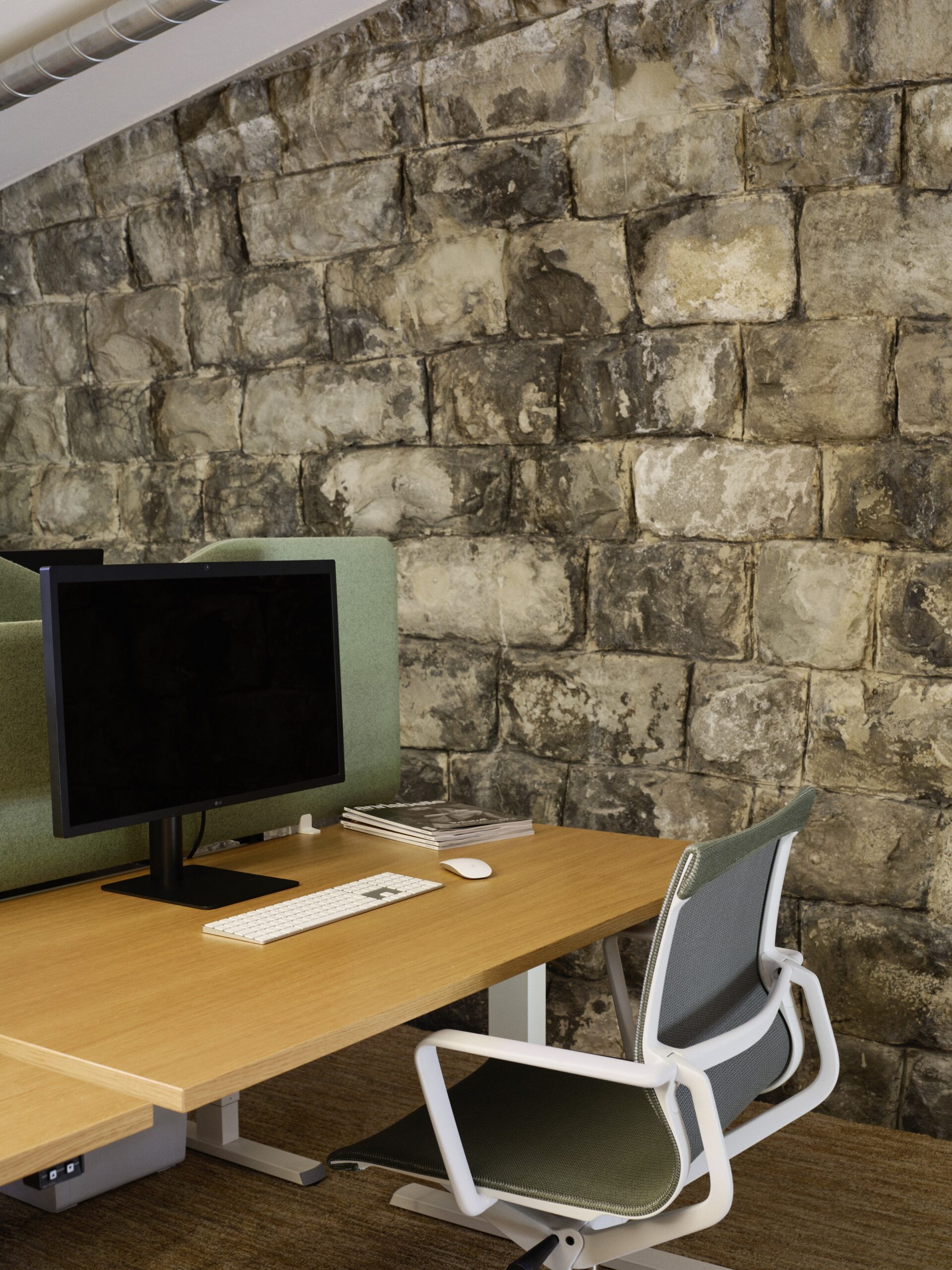 Minimalistischer Arbeitsplatz mit Steinmauer im Hintergrund